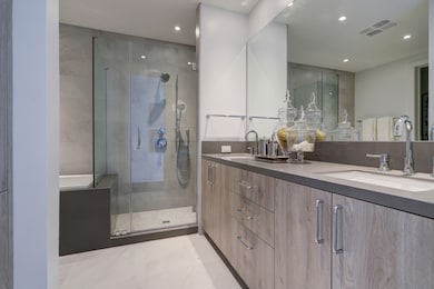 Primary bathroom outfitted with dual vanities, fra