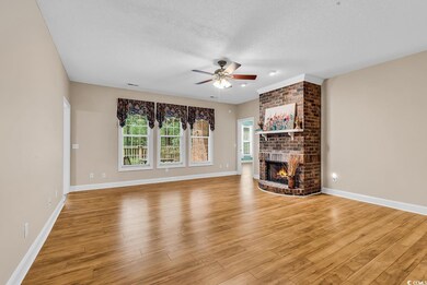 Unfurnished living room featuring ceiling fan, a brick fireplace, light wood-style floors, a textured ceiling, and baseboards