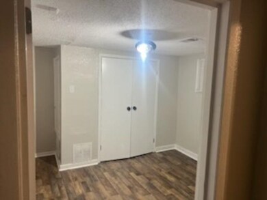Interior space with a textured ceiling, dark hardw