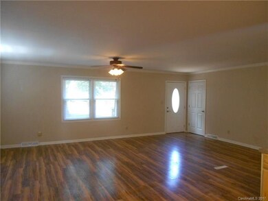 Open floor plan with laminate floors, crown molding, ceiling fan and neutral paint.