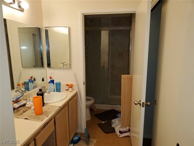 Bathroom featuring a marble finish shower, vanity, and light tile patterned floors