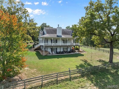 Back of property featuring a large porch, a chimney, stairway, a fenced backyard, and a rural view