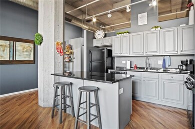Kitchen featuring a breakfast bar area, white cabinetry, a sink, and black appliances