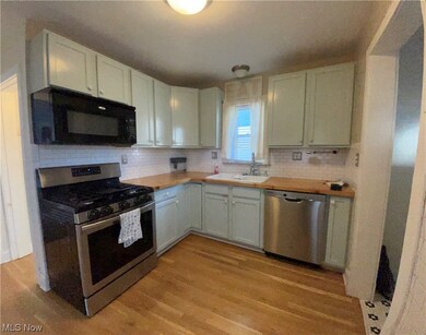 Kitchen with light hardwood / wood-style floors, wood counters, sink, and appliances with stainless steel finishes