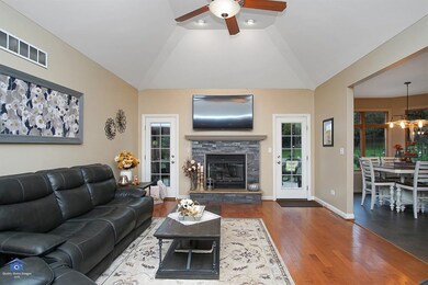 Living room with hardwood floors and tray ceilings. Doors leading to back patio