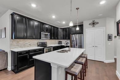 Kitchen featuring decorative light fixtures, stainless steel appliances, tasteful backsplash, a kitchen bar, and sink
