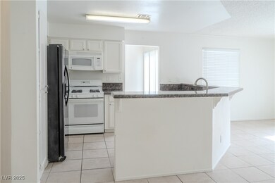 Kitchen with white appliances, white cabinets, lig