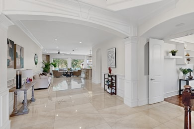 Hallway featuring a decorative wall, wainscoting, arched walkways, light marble finish floors, and recessed lighting