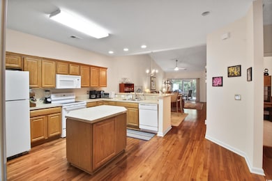 Kitchen with lofted ceiling, white appliances, a peninsula, ceiling fan, and light countertops