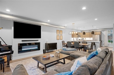 Living area with recessed lighting, light wood finished floors, and a glass covered fireplace