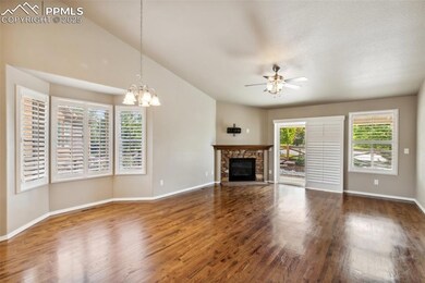 Unfurnished living room featuring wood finished floors, a fireplace, baseboards, a ceiling fan, and lofted ceiling