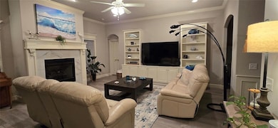 Living area featuring a ceiling fan, crown molding