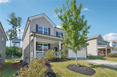 View of front of house featuring a porch, a front yard, brick siding, and concrete driveway