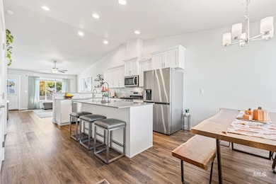 Kitchen featuring white cabinets, a kitchen island, appliances with stainless steel finishes, a kitchen bar, and decorative backsplash