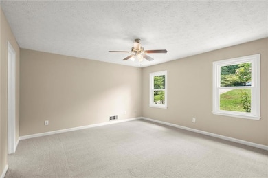 Spare room with a ceiling fan, light colored carpet, and a textured ceiling