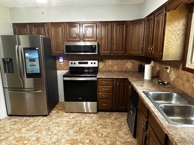 Kitchen with appliances with stainless steel finishes, dark brown cabinets, backsplash, a textured ceiling, and light countertops