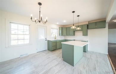 Kitchen with green cabinetry, a chandelier, a center island, pendant lighting, and recessed lighting