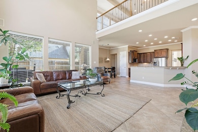 Living area featuring a towering ceiling, light tile patterned floors, ornamental molding, and recessed lighting