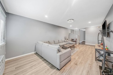 Living area with light wood finished floors and recessed lighting