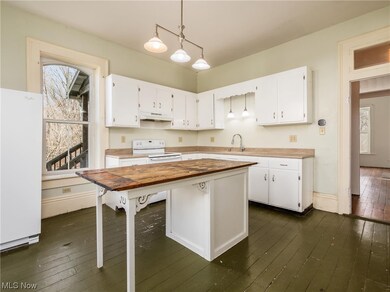 Kitchen featuring dark wood-type flooring, white cabinetry, and white appliances