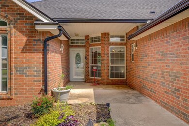 Entrance to property featuring a shingled roof, brick siding, and a patio area