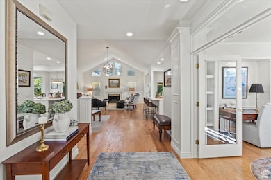 Entrance foyer with lofted ceiling, a glass covered fireplace, a chandelier, light wood-type flooring, and recessed lighting