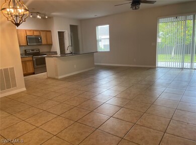 Kitchen featuring sink, ceiling fan with notable chandelier, stainless steel appliances, light tile patterned floors, and decorative light fixtures