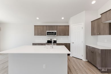 Kitchen with appliances with stainless steel finishes, light wood finished floors, modern cabinets, recessed lighting, and an island with sink