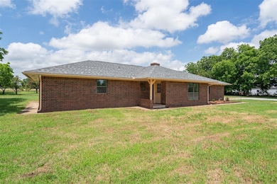 Rear view of house featuring a yard, brick siding, and a chimney
