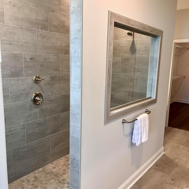 Bathroom featuring a tile shower and a spacious closet
