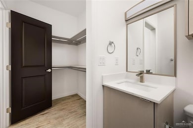 Bathroom featuring toilet, baseboards, vanity, and wood finished floors