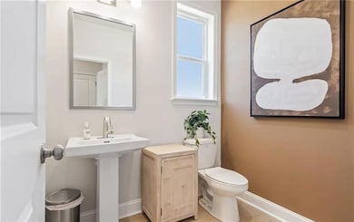 Half bath with toilet, baseboards, and a sink