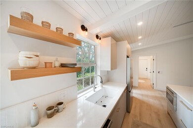 Kitchen with light countertops, a sink, and open s