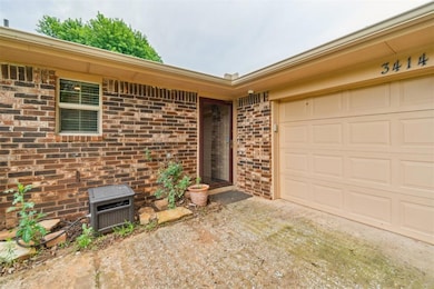 View of exterior entry featuring brick siding, driveway, and a garage