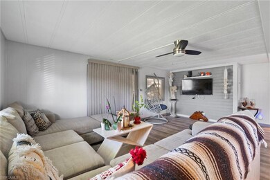 Living room with wood walls, ceiling fan, and hard