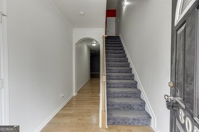 Stairs featuring arched walkways, wood finished floors, and crown molding