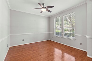 Empty room with crown molding, wood finished floors, and a ceiling fan