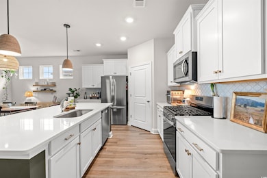 Kitchen with appliances with stainless steel finishes, a sink, recessed lighting, light wood-style flooring, and light countertops