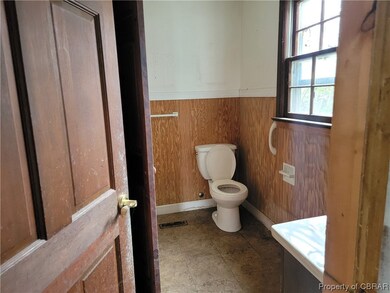 Bathroom featuring toilet, wood walls, and tile fl
