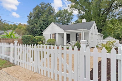 Bungalow-style house featuring a fenced front yard, covered porch, brick siding, a chimney, and a gate