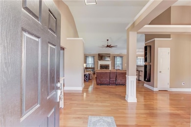 Entrance foyer featuring a fireplace, a ceiling fan, light wood-type flooring, and baseboards