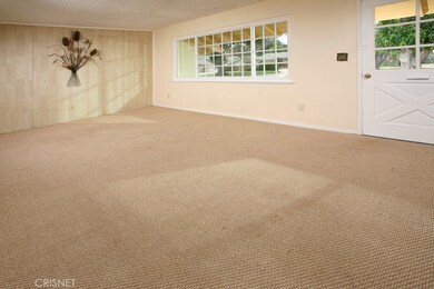 The formal living room is drenched in natural light from a multitude of windows and is enhanced by rich low-pile wall-to-wall carpet.