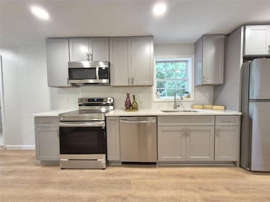 Kitchen featuring appliances with stainless steel finishes, gray cabinets, light wood finished floors, and recessed lighting
