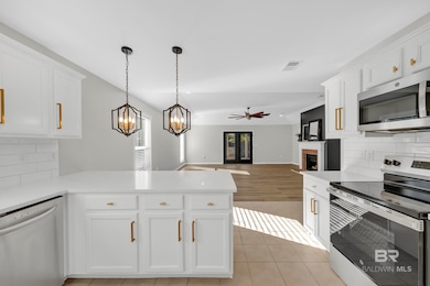 Kitchen featuring tasteful backsplash, stainless steel appliances, white cabinets, light tile patterned flooring, and vaulted ceiling