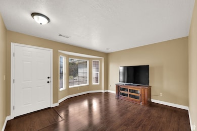 Entrance foyer with a textured ceiling and dark wood-style floors