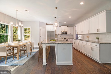 The Kitchen is a true Showstopper featuring a Huge Granite Island, Stainless Steel Appliances, White Cabinets, a Walk-In Pantry, Classic White Tile Backsplash, and a Breakfast Nook wrapped in Windows