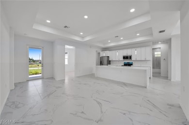 Unfurnished living room with a tray ceiling, light marble finish floors, and recessed lighting