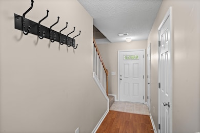 Entryway featuring a textured ceiling, stairs, and wood finished floors