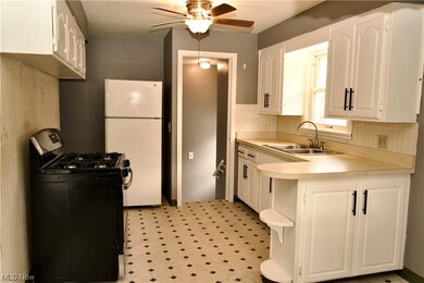 Kitchen with sink, white fridge, white cabinetry, and light tile floors