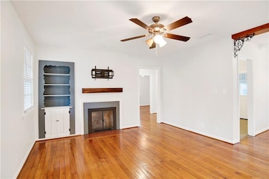 Unfurnished living room featuring light wood-style floors, a brick fireplace, plenty of natural light, and ceiling fan